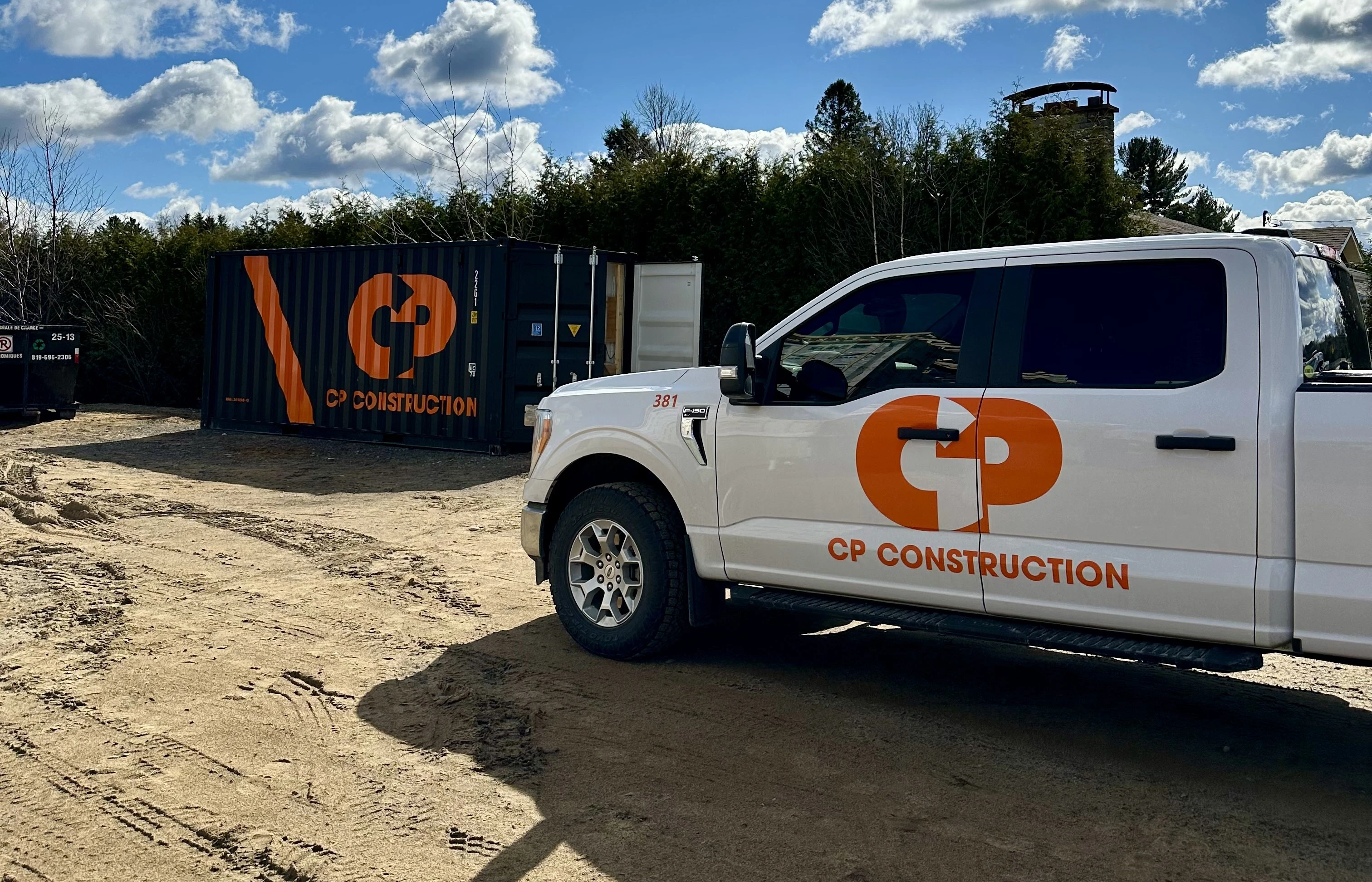 Camion et conteneur CP Construction sur un site en Mauricie, mettant en avant leur expertise en construction résidentielle et industrielle.